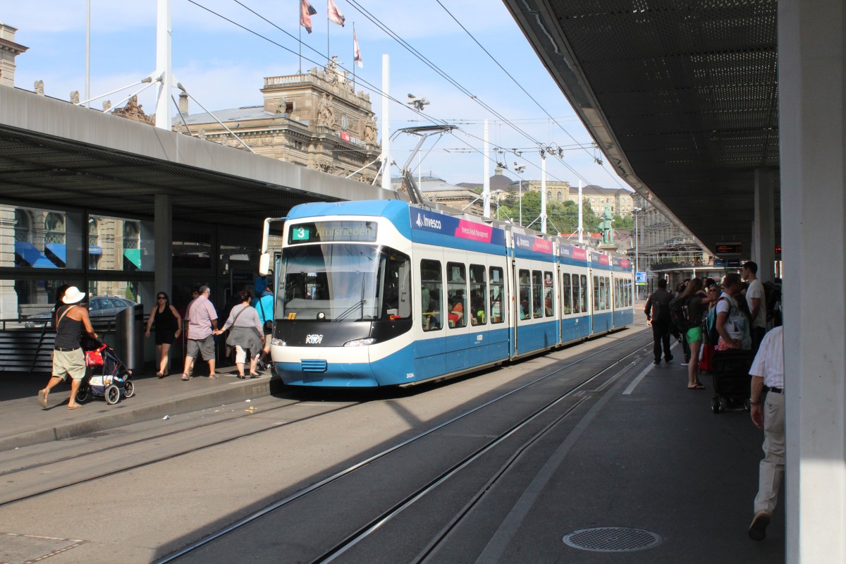 Ein blau-weisses Tram und wartende Fahrgäste am Zürcher Bahnhofplatz.
